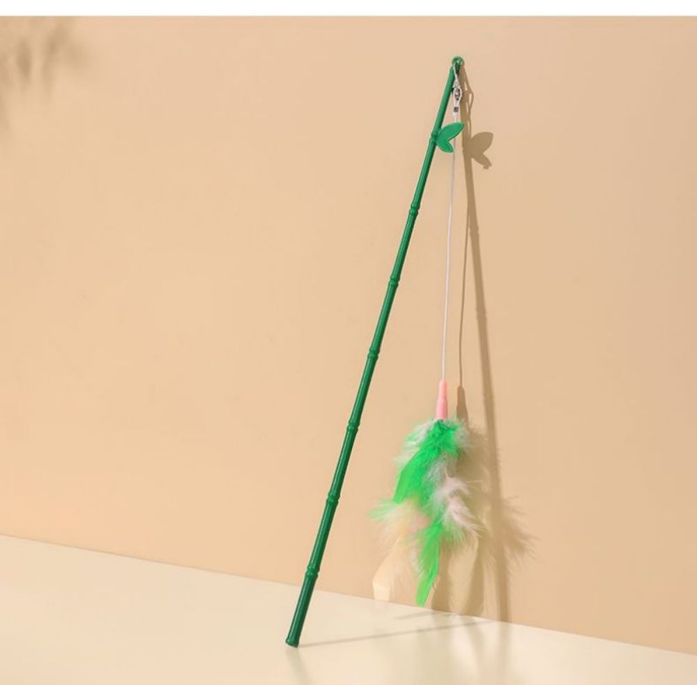 Green feather wand cat toy on a clean beige background
